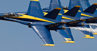 a group of blue and yellow jets flying in the sky