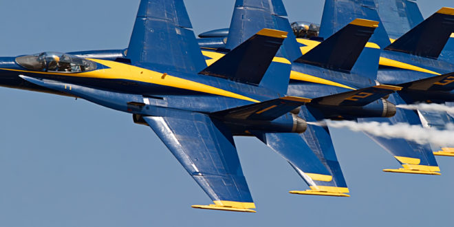 a group of blue and yellow jets flying in the sky