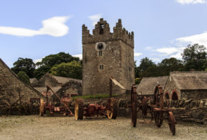 a stone tower with a clock tower and farm equipment
