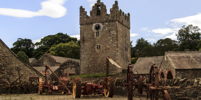 a stone tower with a clock tower and farm equipment