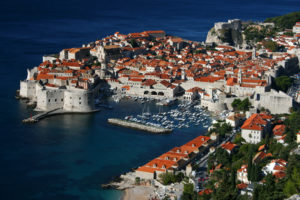 an aerial view of a city with red roofs and boats on the water