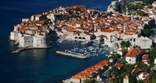 an aerial view of a city with red roofs and boats on the water