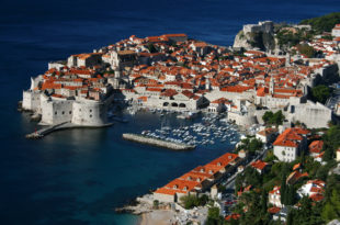 an aerial view of a city with red roofs and boats on the water