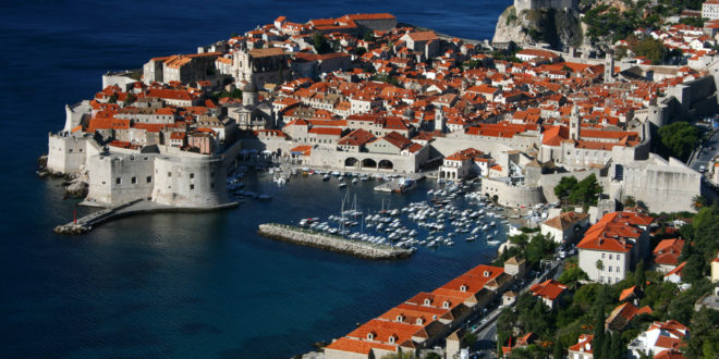 an aerial view of a city with red roofs and boats on the water
