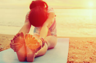 a woman doing yoga on the beach