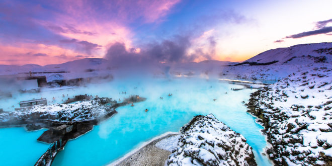 a blue water with snow and a pink sky