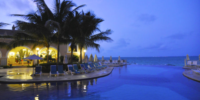 a pool with chairs and palm trees by it