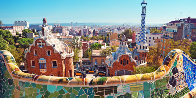 a colorful tiled wall with Park Güell in the background