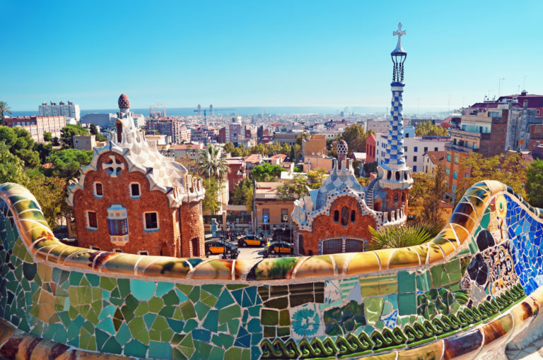 a colorful tiled wall with Park Güell in the background