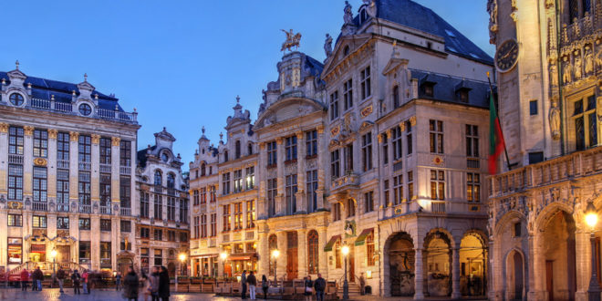 a group of people walking in a plaza with Grand Place in the background