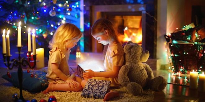 two girls sitting on the floor with a gift box and a teddy bear